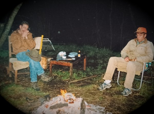 Dave playing the harmonica and Mike playing the handle castanet, jamming around a bed of hot coals.